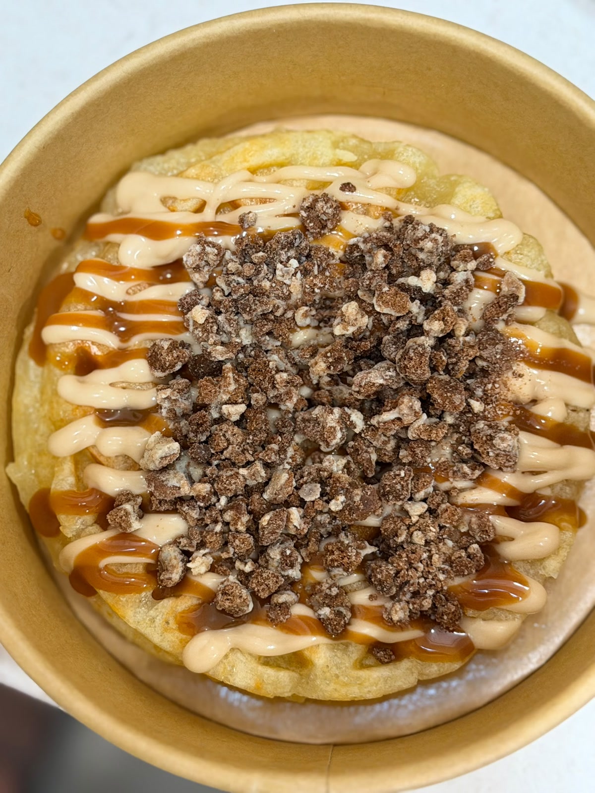 Gofre de queso visto desde arriba, con crema, caramelo y crunch de chocolate