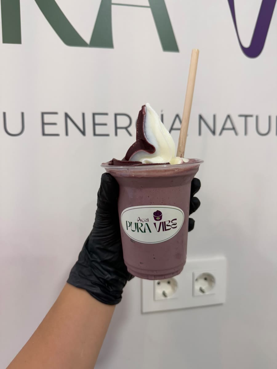 Un vaso de açaí con el remolino recién servido, delante del rótulo de la pared